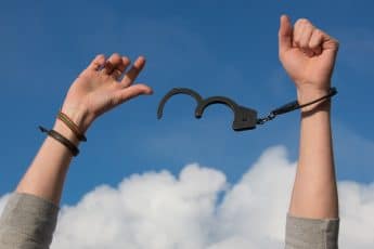 hands raised to the sky breaking free of handcuffs | Bankruptcy
