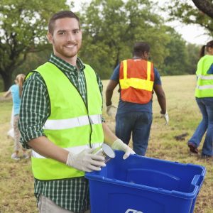 Man holding a recycling Bin at a park clueanup | Community Services
