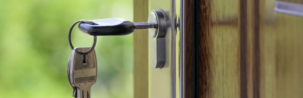 Key hanging in a polished wooden door | Buying a House