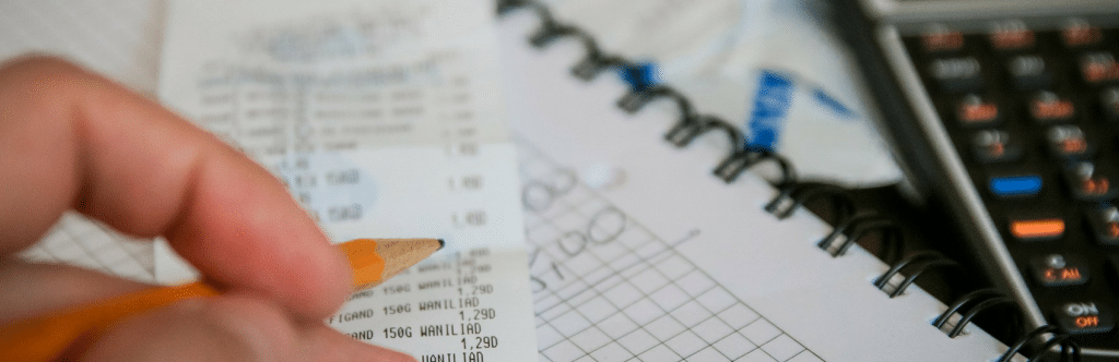 Paying off post Holiday Debt. Close up image of a receipt and a person's hand holding a pencil